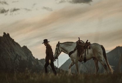 Person walking with horse across Montana fields